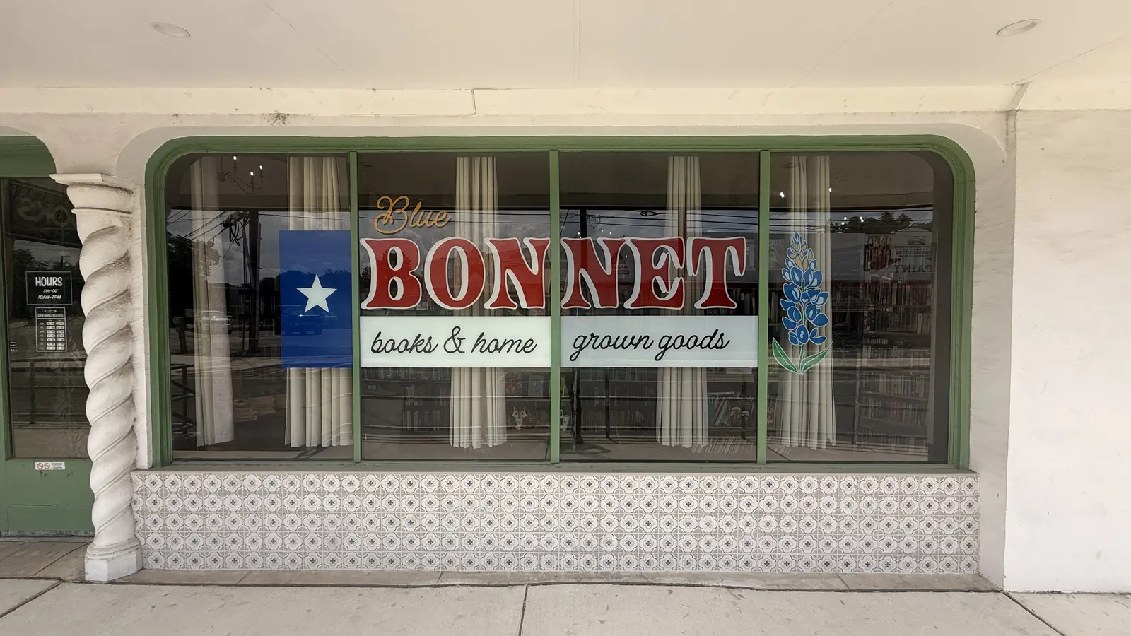 Close-up of the hand-painted Blue Bonnet books and home grown goods window sign with the Texas flag and a bluebonnet flower.