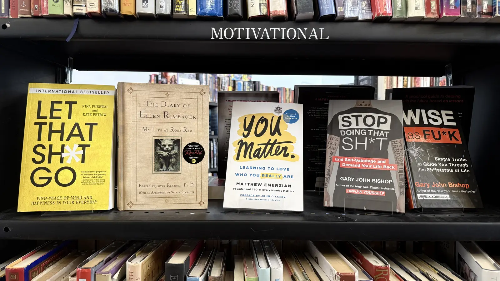 Motivational section shelf featuring Let That Sh*t Go, You Matter, and Stop Doing That Sh*t.