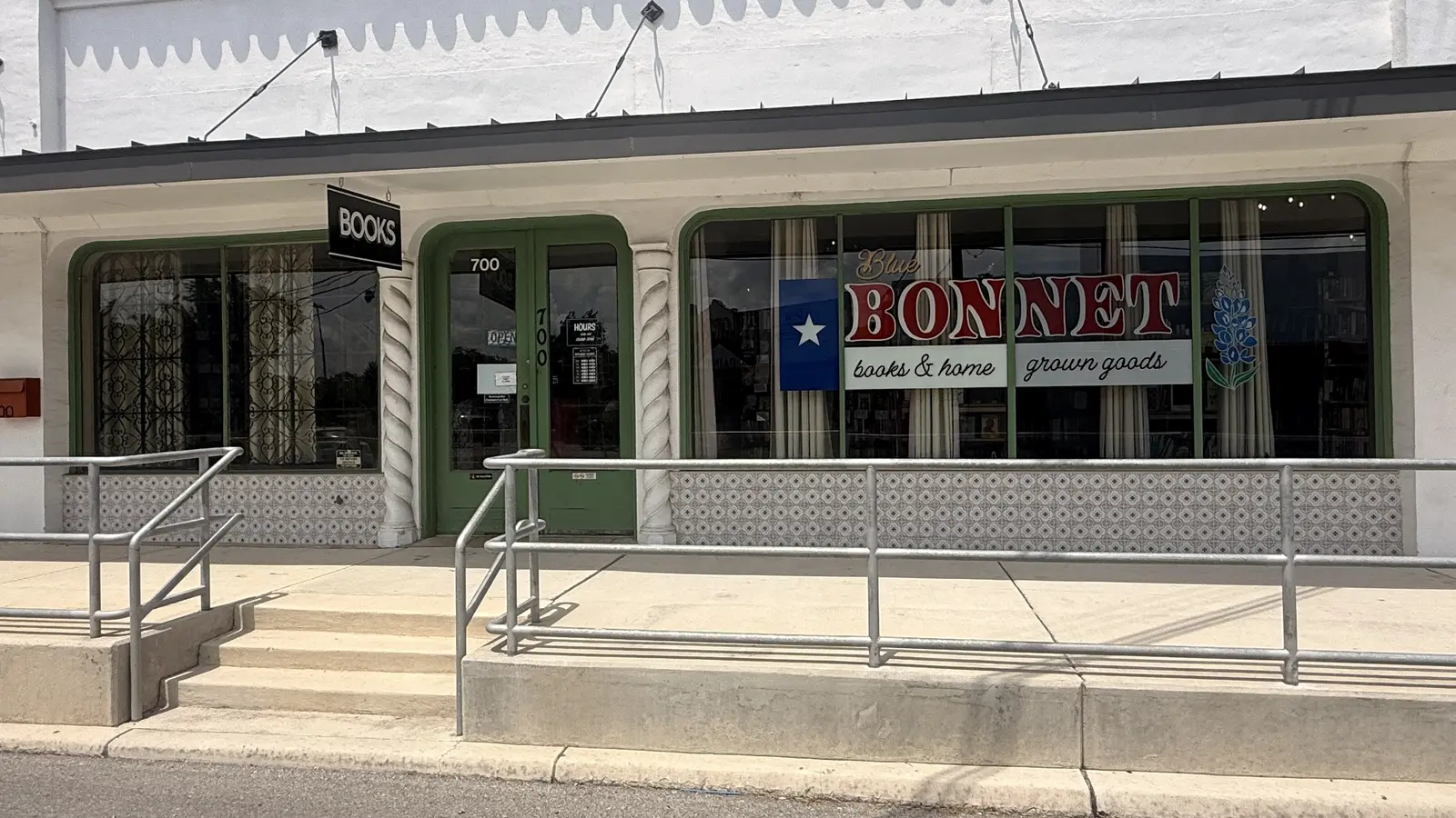 Green-trimmed entrance of Bluebonnet Books & Homegrown Goods with the BOOKS sign out front.