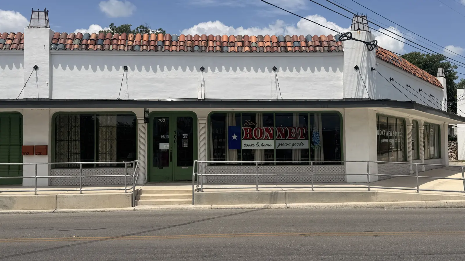 Wide storefront view of Bluebonnet Books & Homegrown Goods next to Honeygrove Tattoo Studio on Fredericksburg Road.